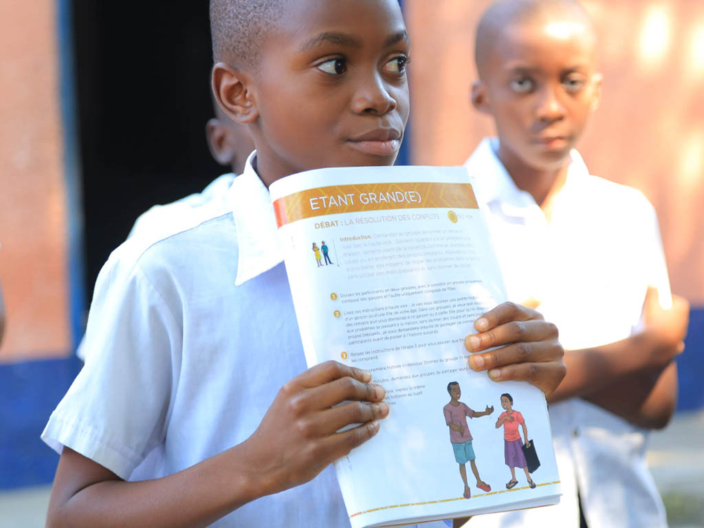 A school boy reading the toolkit for Very Young Adolescents (VYA) that contains information about Sexual and Reproductive Health (SRH)