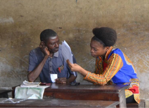 Une jeune évaluatrice mène un entretien avec un parenttuteur homme à Kinshasa, en RDC